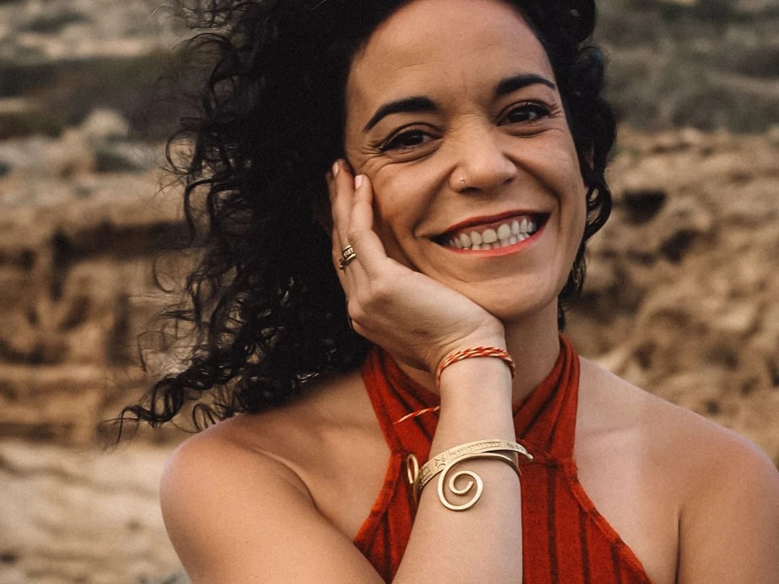 Portrait of Esther Gómez smiling, hair down, the sea behind her.
